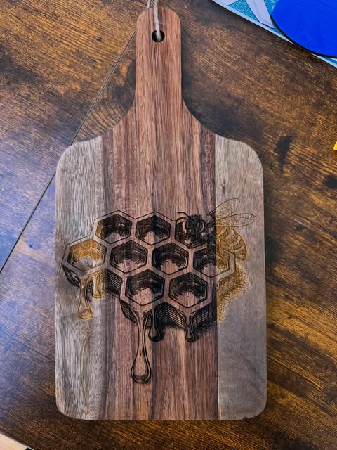 Walnut charcuterie board engraved with dripping honeycomb and a bee